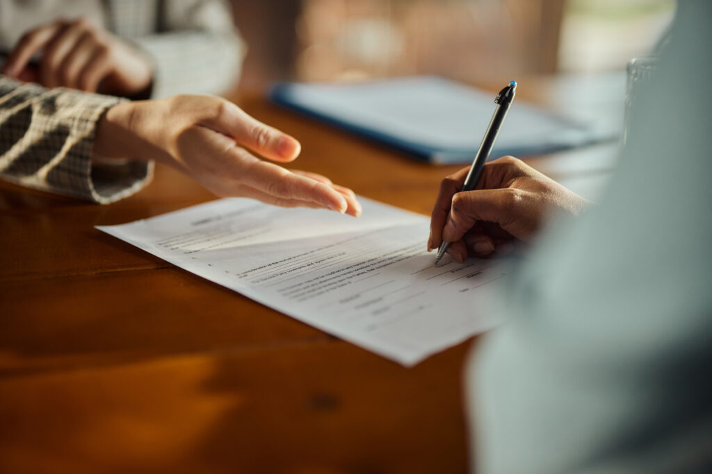 Close up of black woman signing a contract during a meeting with her agent in the office